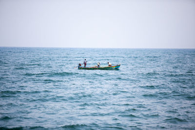 People in boat sailing on sea against clear sky