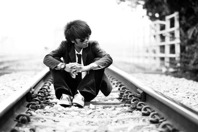 Businessman sitting on railroad track