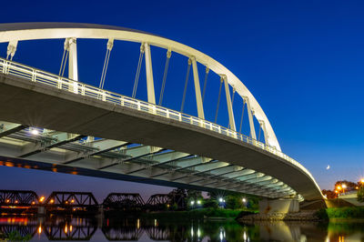 Low angle view of bridge over river against blue sky