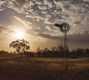 Windmill on field against sky at sunset