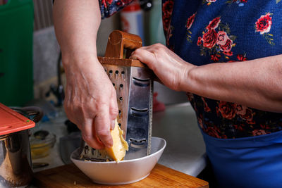Close-up view of senior white woman grates cheese