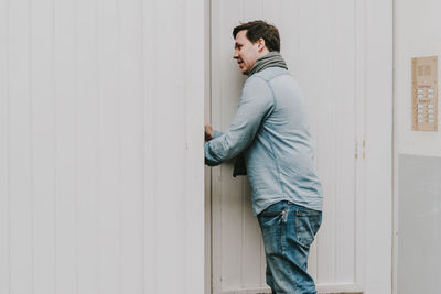 Side view of young man entering house