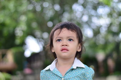 Cute girl looking away against trees