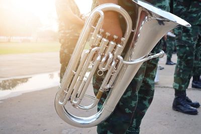 Midsection of army soldier holding saxophone