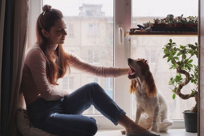 Smiling woman with dog sitting at home