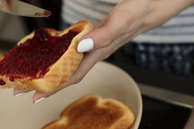 Cropped hand applying jam on bread