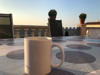 Close-up of coffee cup on table against clear sky