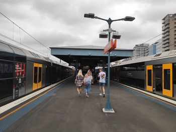 People waiting train at railroad station platform against sky