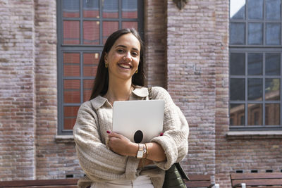 Portrait of a smiling young woman looking through window