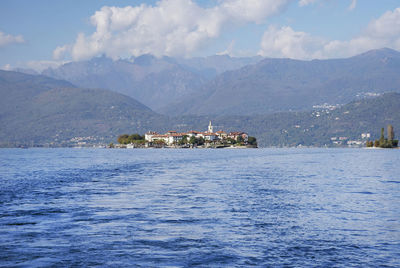 Scenic view of sea by buildings and mountains against sky