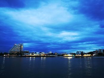 City at waterfront against cloudy sky