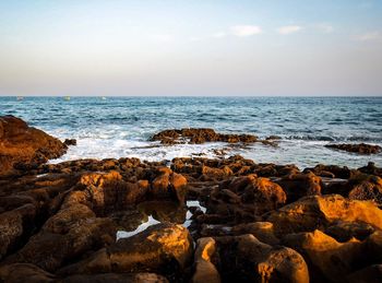 Scenic view of rocks on beach against sky