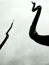 Low angle view of silhouette sculpture on street against sky