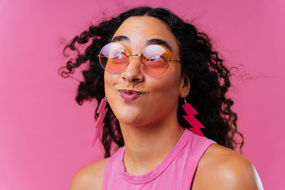 Portrait of young woman standing against yellow background