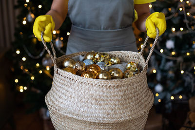 Preparing for christmas. basket with new year's decorations of gold color in hands. xmas atmosphere