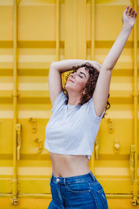 Full length of woman standing against yellow wall