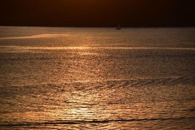 Silhouette of sailboat in sea during sunset