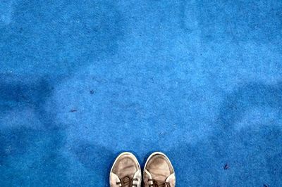 Low section of shoes standing on blue carpet