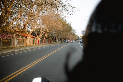 Road amidst trees against sky seen through car windshield