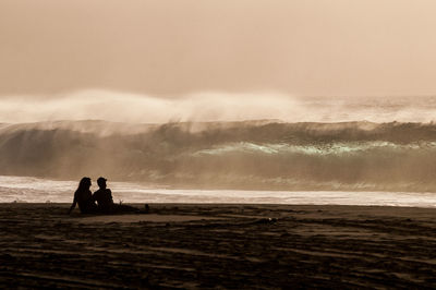 Silhouette of couple sitting at beach