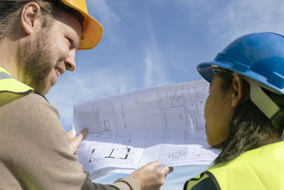 People on construction site holding blueprint
