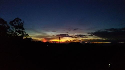 Silhouette trees against dramatic sky during sunset