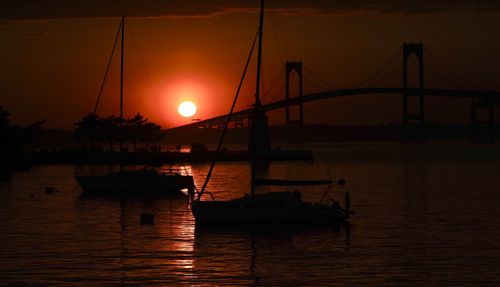 Silhouette bridge over river against sky during sunset