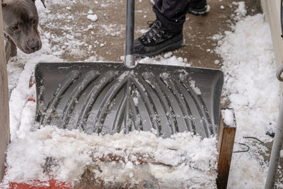 Low section of man cleaning snow on road