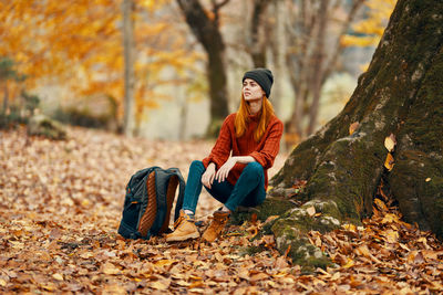 Man sitting on leaves during autumn