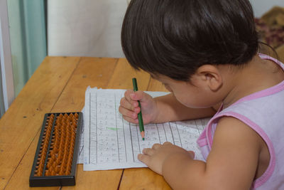 Side view of boy studying on table at home