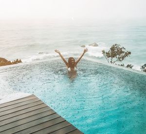 Rear view of shirtless man in sea against sky