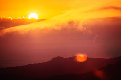 Silhouette mountains against dramatic sky during sunset