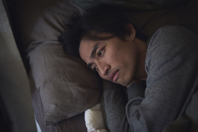 Sad man facing depression lying in bed