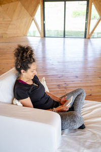 Side view of woman sitting on sofa at home