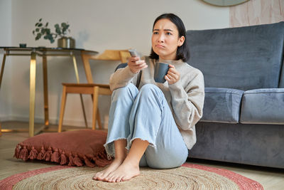 Portrait of young woman sitting on sofa at home