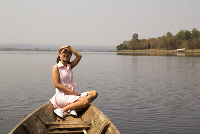 Young woman sitting on boat by sea against clear sky