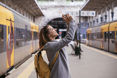 Rear view of woman standing by train at railroad station