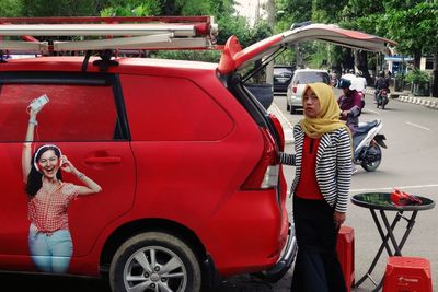 Young woman standing in car