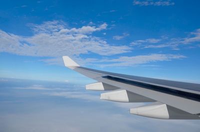 Airplane flying over clouds in blue sky