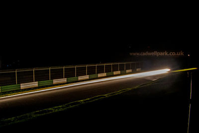 Light trails on road against sky at night