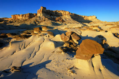 Barren landscape with rocky structure against clear sky