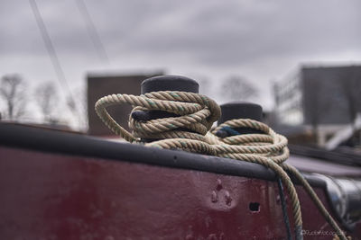 Close-up of rope tied on metal against sky