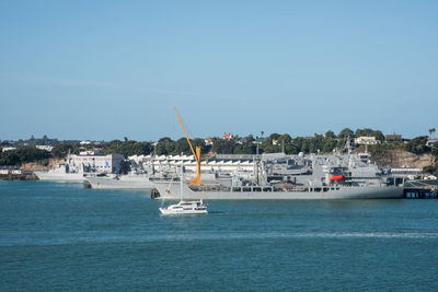 Sailboats on sea by buildings against clear sky