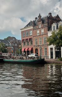 Buildings by canal against sky in city