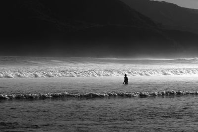 Silhouette people on sea shore against sky