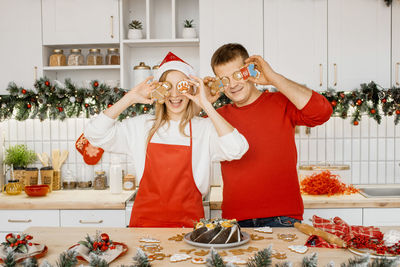 Attractive woman standing next to her husband. both having fun with homemade gingerbread cookies.