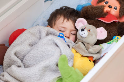 Cute baby is sleeping in a box with his toys