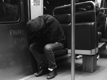 Man wearing hooded shirt sitting in train