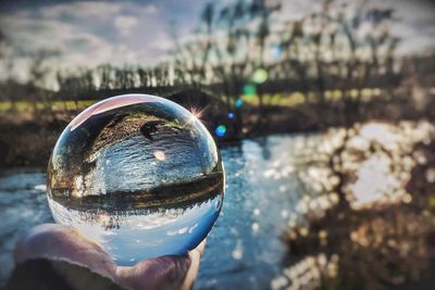 Close-up of hand holding crystal ball against blurred background