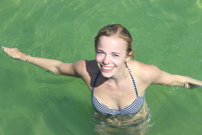 High angle portrait of beautiful woman with arms outstretched swimming in pool